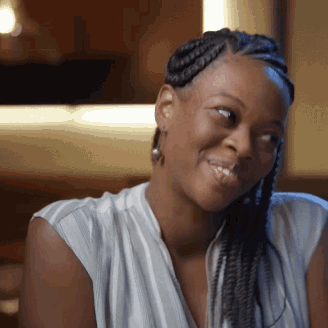 a woman with braids is smiling and wearing a striped shirt