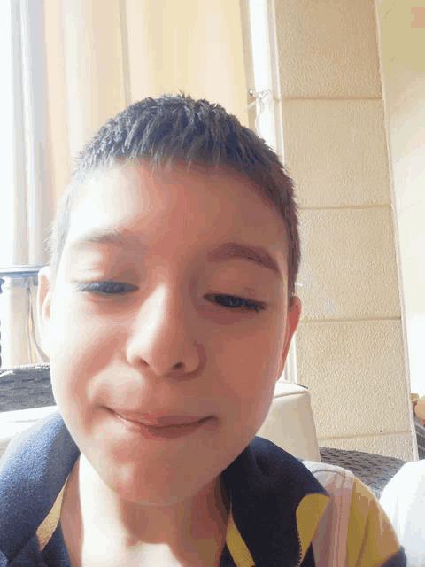 a young boy wearing a yellow and black shirt looks at the camera