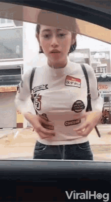 a woman in a white shirt is standing in a car holding a cup .