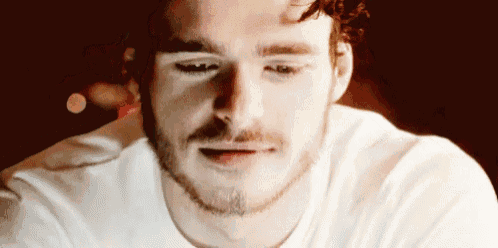 a close up of a man 's face with a beard and a white shirt .