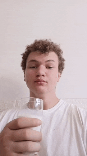 a young man holds up a glass of milk