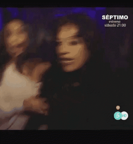 two women are dancing in front of a sign that says ' septimo ' on it .