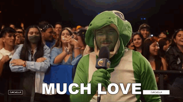 a man in a frog costume is holding a microphone and the words much love are above him