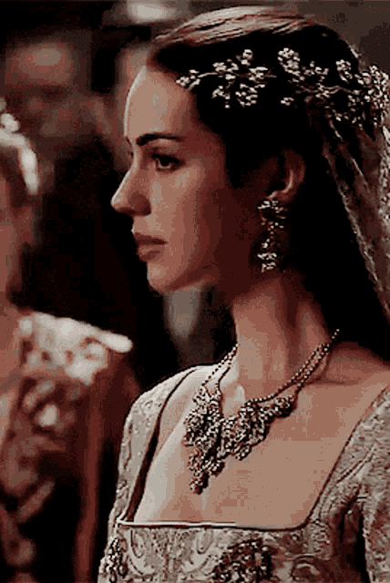 a woman wearing a necklace and earrings has a veil in her hair