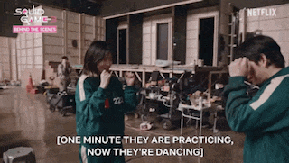 a man and a woman are dancing in a room in a squid game behind the scenes video .