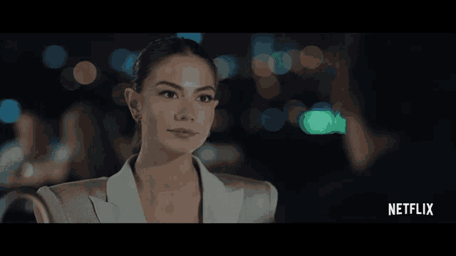 a woman in a white suit is looking at a man in a black shirt with netflix written on the bottom