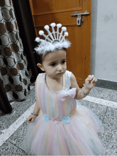 a little girl wearing a rainbow dress and a crown
