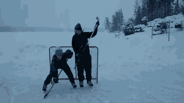 a person holding a hockey stick stands next to a person holding a hockey stick