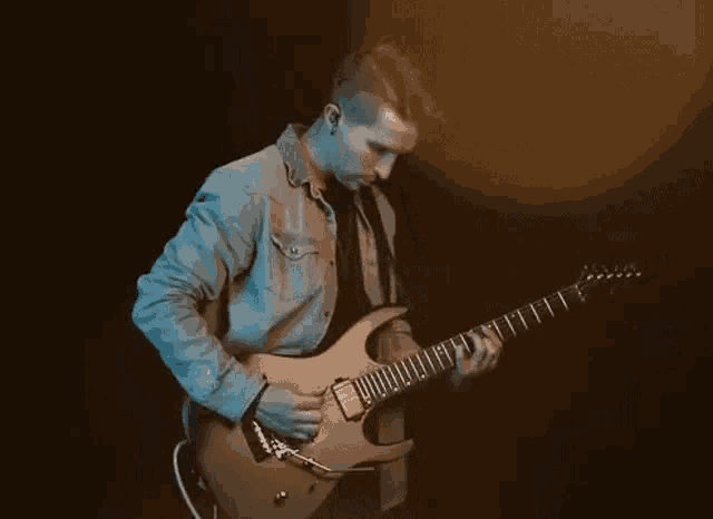 a young man is playing a guitar in a dark room .