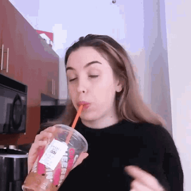 a woman drinking from a cup that says dunkin ' donuts on it