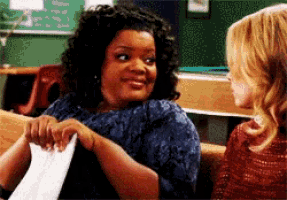 a woman is holding a piece of paper and smiling while sitting next to another woman