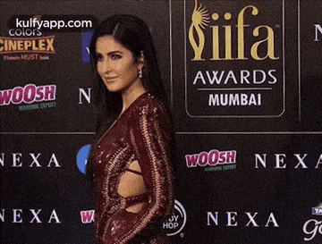 a woman in a red dress is standing in front of a wall that says iifa awards .
