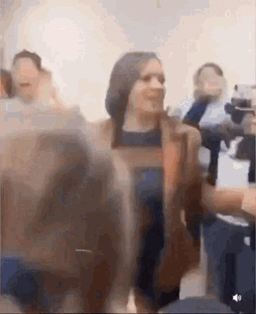 a woman in a brown jacket is sitting in a crowd of people on a plane .