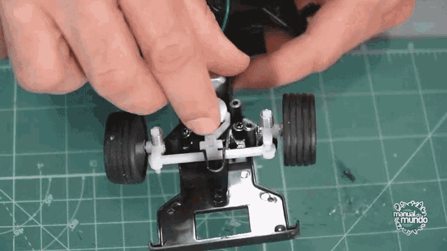 a person is working on a model car with the words manual del mundo visible in the corner
