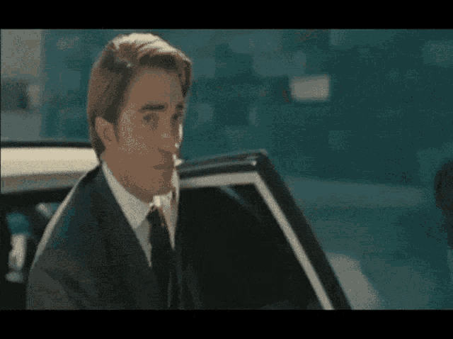 a man in a suit and tie is getting into a car