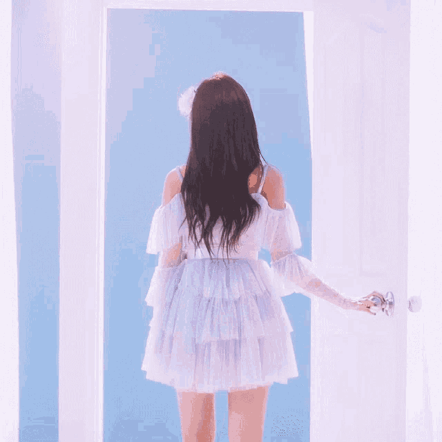 a woman in a white dress opens a door