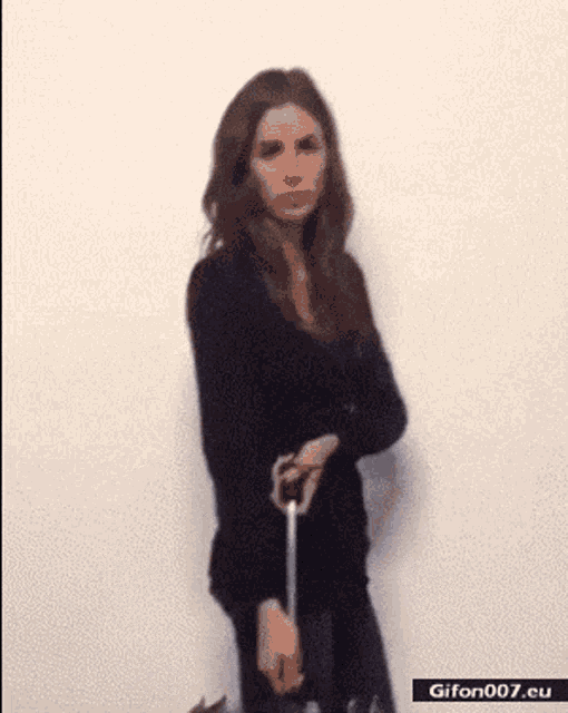 a woman is standing in front of a white wall with a gif on the bottom right that says gifon007.eu
