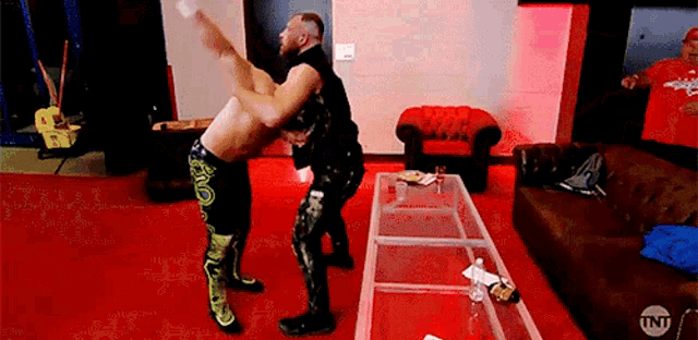two men are wrestling in a living room with a couch and a table .