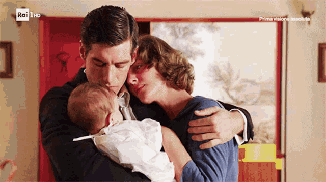 a man and woman holding a baby in front of a tv screen that says rai hd