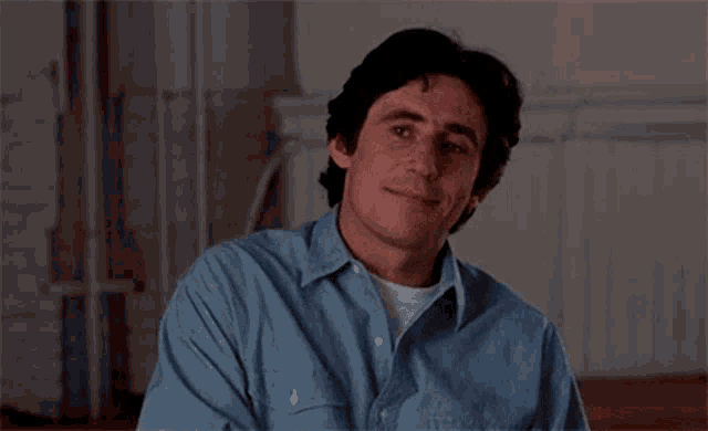 a man in a blue shirt is smiling while sitting down