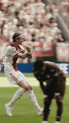 a soccer player is jumping in the air while another player watches