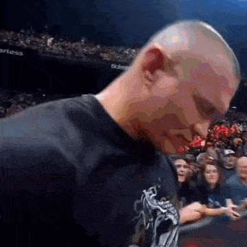 a man in a black shirt with a skull on it stands in front of a crowd .