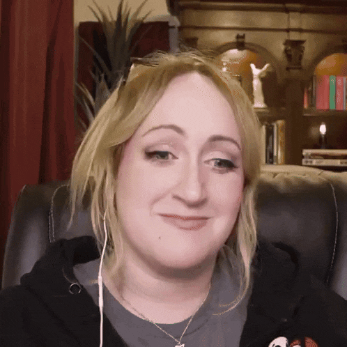 a woman wearing headphones and a necklace is sitting in a chair and smiling