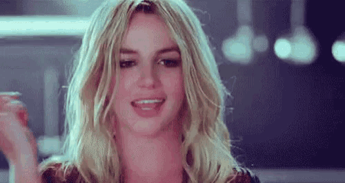 a close up of a woman with blonde hair making a funny face and smiling .