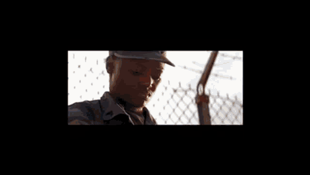 a woman in a military uniform stands in front of a barbed wire fence .