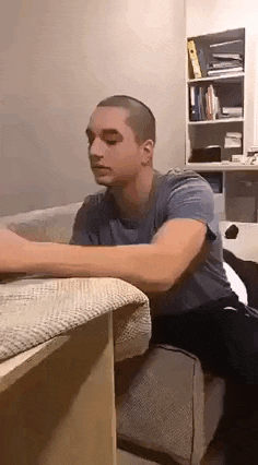 a man is sitting at a table in a living room with his arms outstretched .