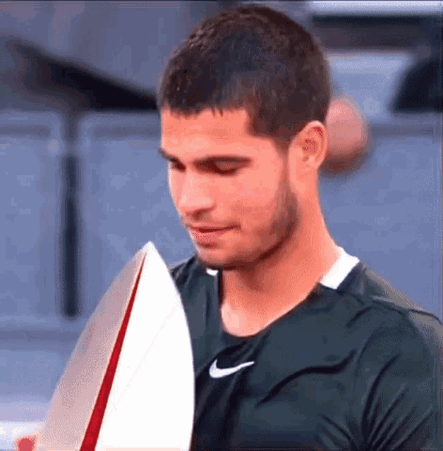 a man in a green nike shirt is holding a trophy