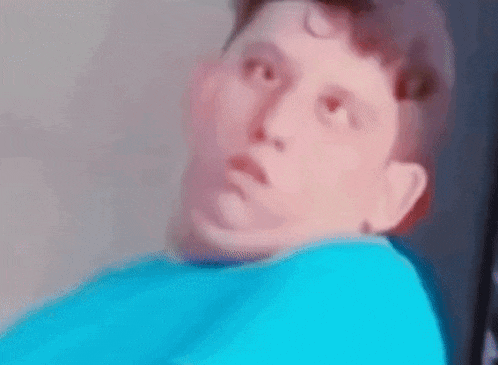 a young boy in a blue shirt is making a funny face while looking up .