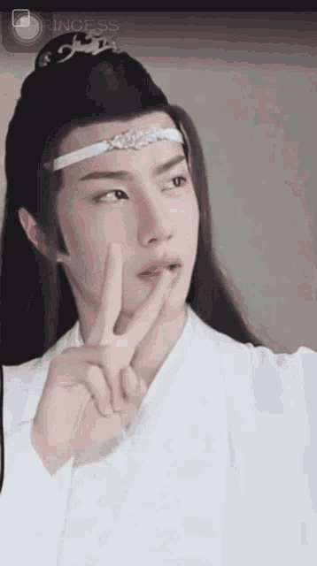 a man wearing a headband and a white shirt is making a peace sign