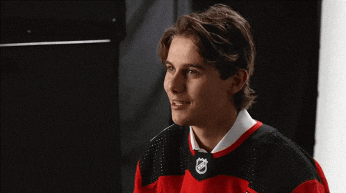 a young man wearing a red and black jersey with the nhl logo on it