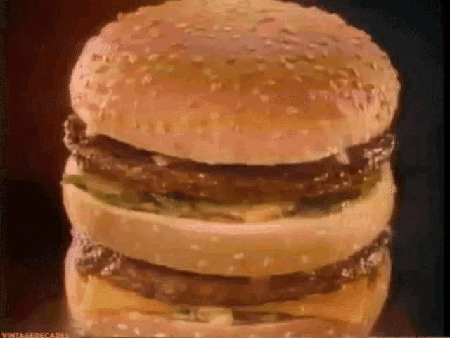 a big mac hamburger is stacked on top of each other on a black background .