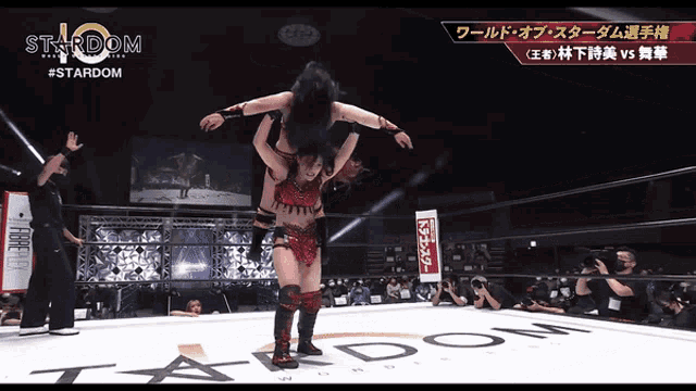 a female wrestler is being lifted in the air by another wrestler in a stardom wrestling ring