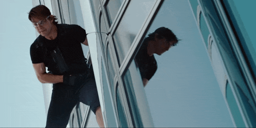 a man in a black shirt and goggles is climbing a building