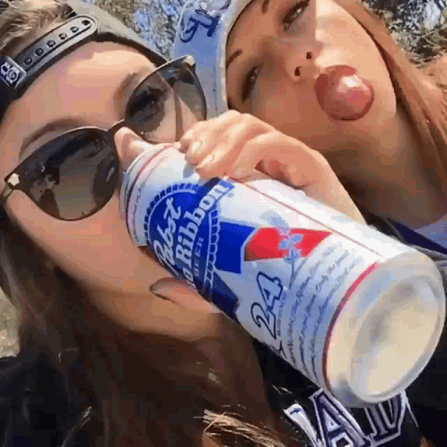 two women are drinking from a can of pabst blue ribbon beer