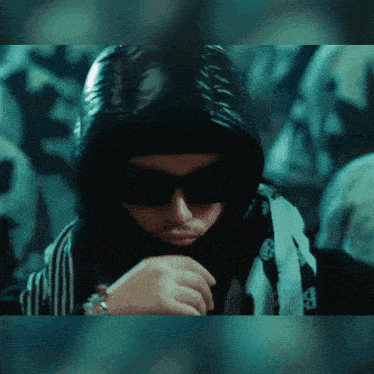a man wearing sunglasses and a scarf around his neck has the letter a on it