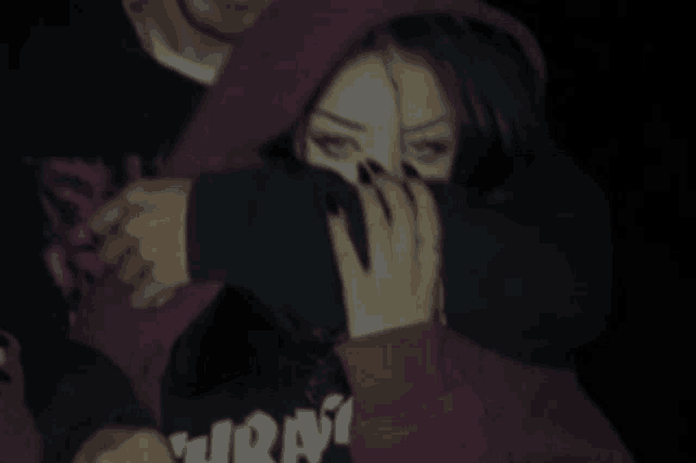 a woman is covering her face with her hands while a man holds her .