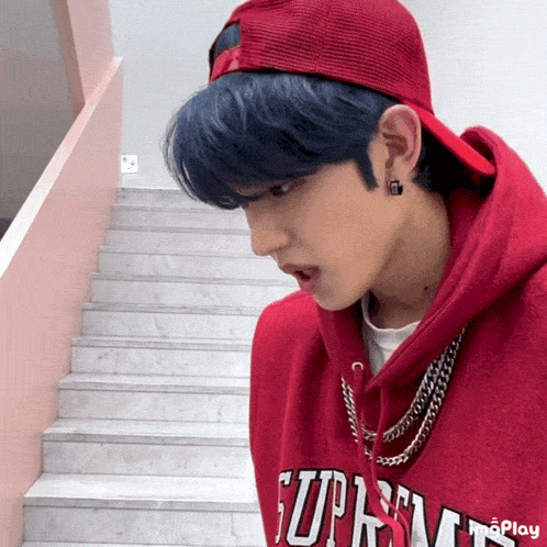 a man wearing a red hoodie that says supreme