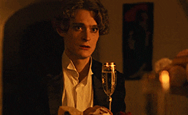 a young man in a tuxedo is holding a glass of champagne