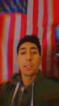 a man is taking a selfie in front of a flag .