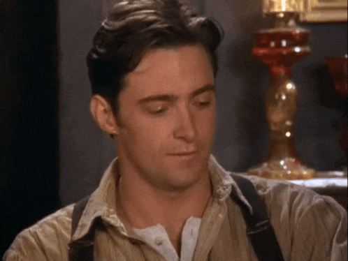 a man in a tan shirt and suspenders looks down