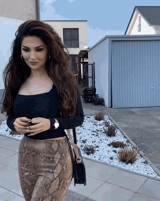 a woman wearing a black top and snakeskin pants