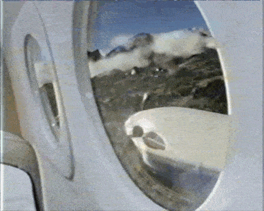 an airplane window shows a view of mountains and clouds