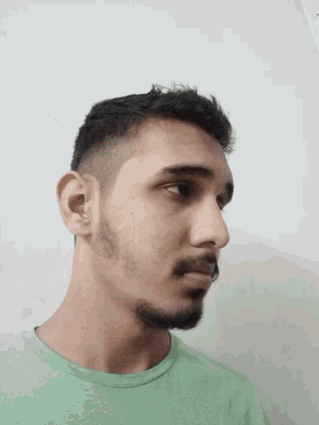a man with a beard wearing a green shirt looks down