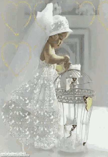 a little girl in a white dress is holding a bird cage with a butterfly inside of it