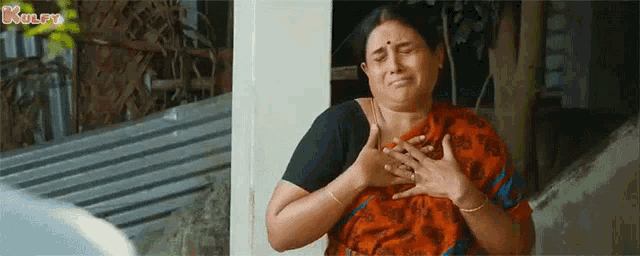 a woman is holding her chest with her hands while crying .