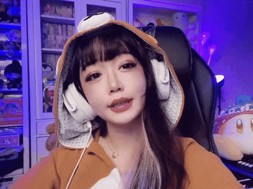 a girl wearing a hoodie and headphones is looking at the camera